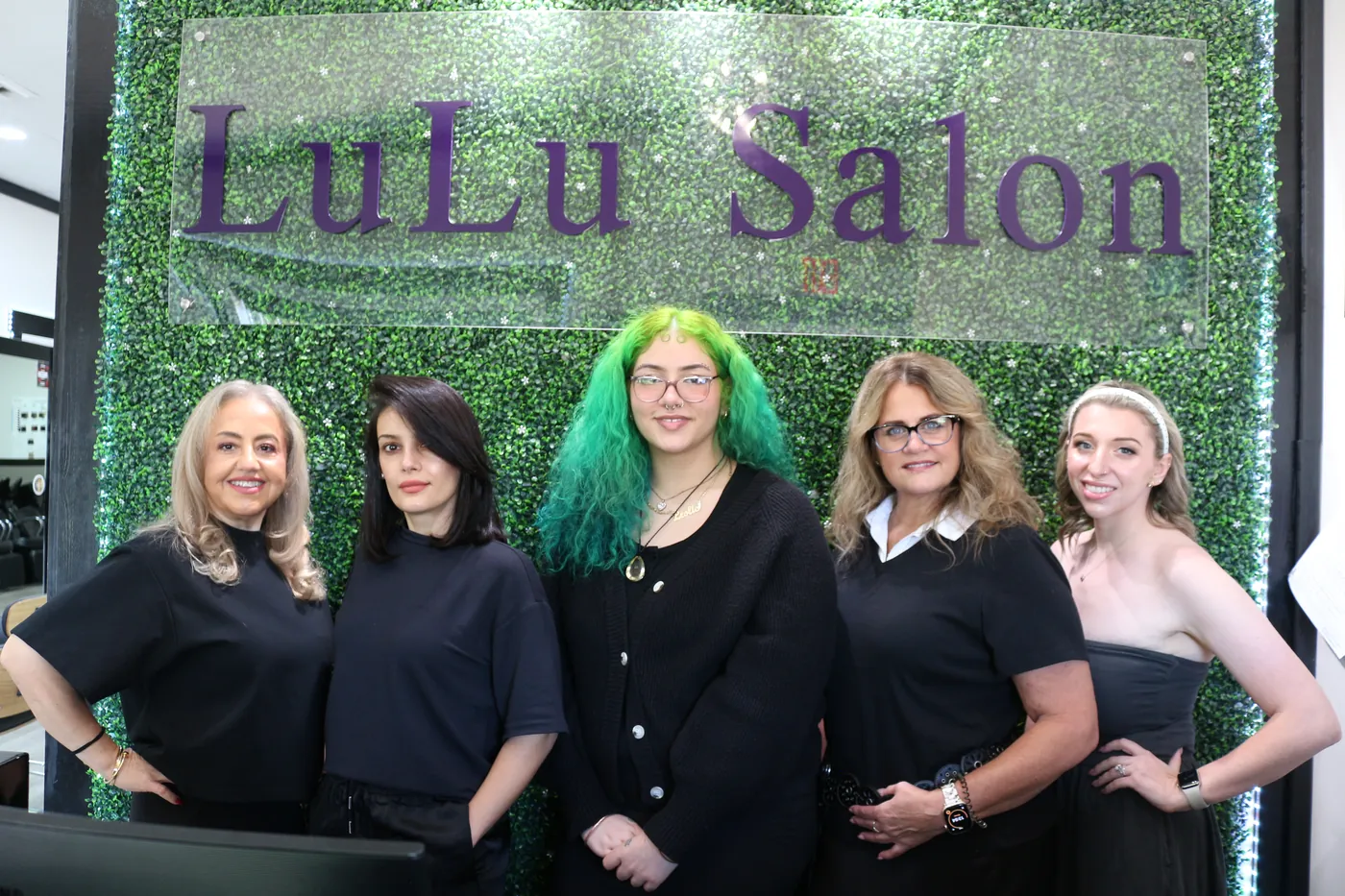 The LuLu Salon team in front of the signature green wall in Waxhaw